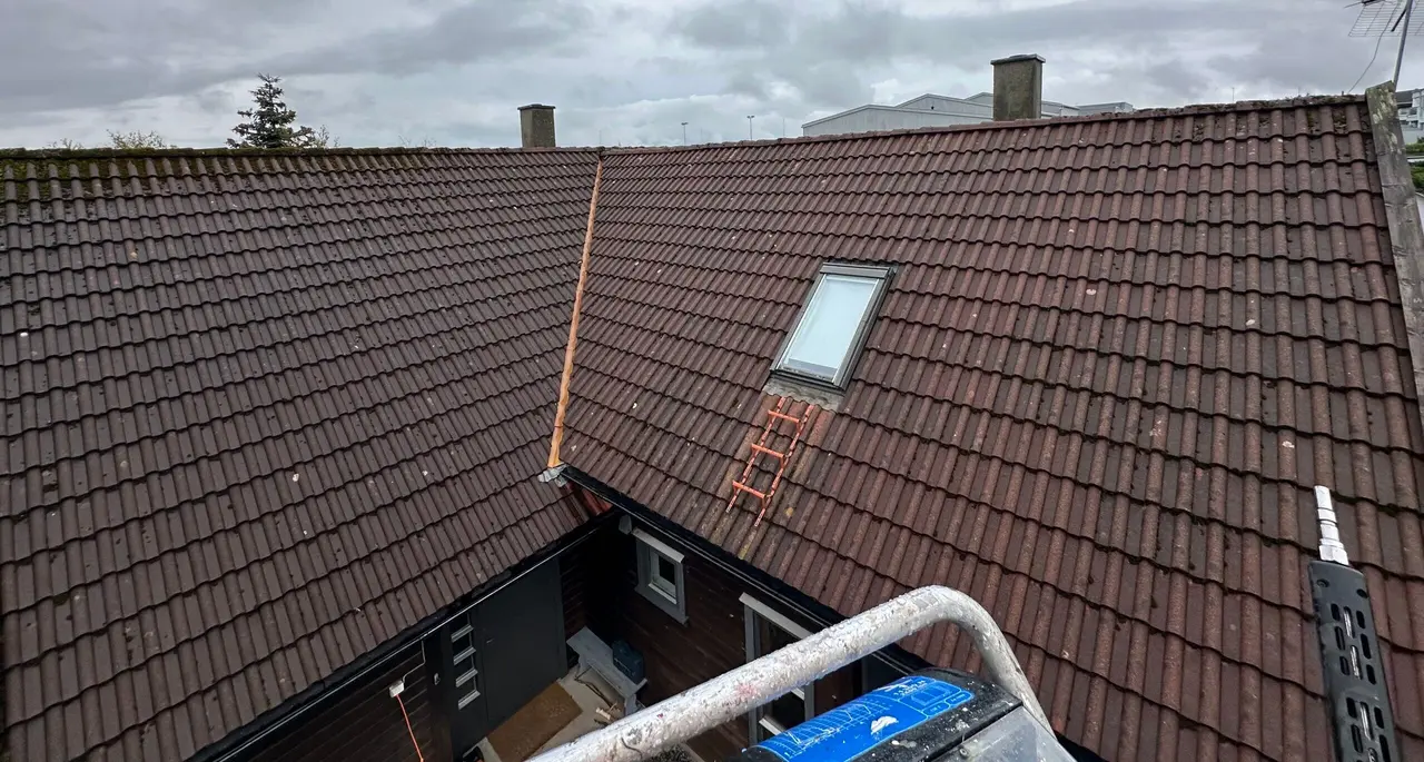 Rødt teglsteinstak med takvindu og stige